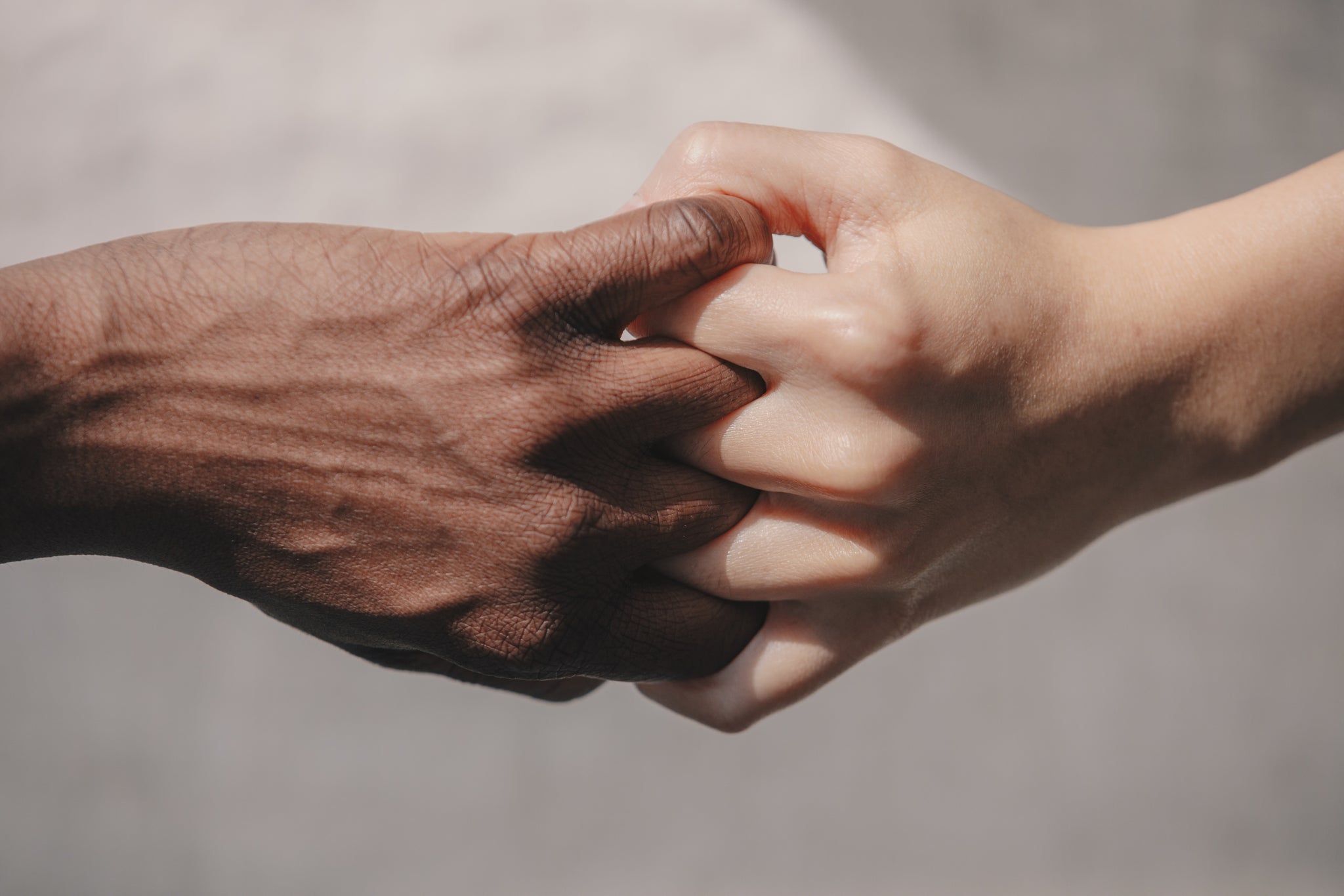 black hand and white hand gripping at knuckles together to show racial unity
